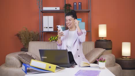 Home-office-worker-young-woman-rejoicing-on-the-phone.